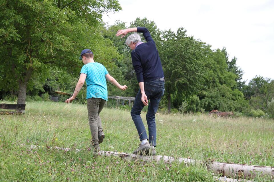Schulbegleiter Stefan Pahlke geht jeden Tag nach dem Lernen mit Dennis raus in die Natur. Hier balancieren die beiden über einen Baumstamm am Fuße des Egelsbergs in Weilheim.